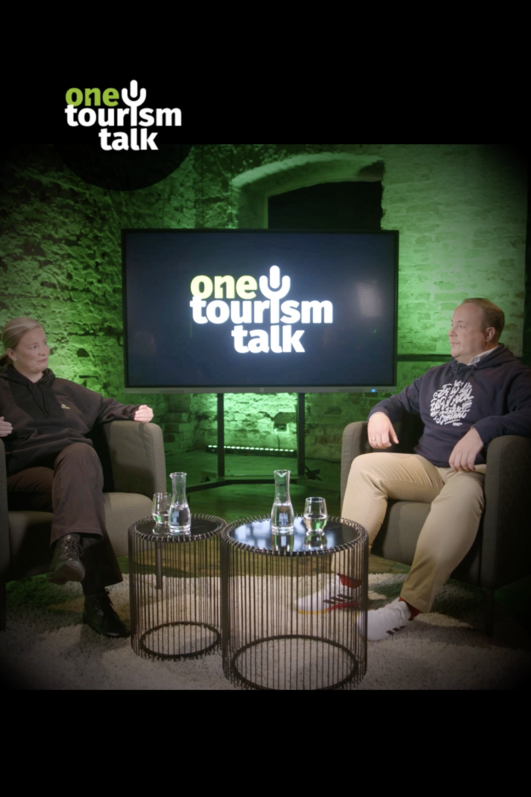 Zwei Erwachsene in einer Talkshow vor grüner Studiokulisse