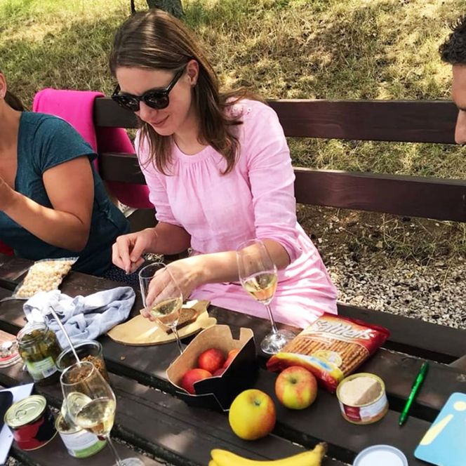 Drei Erwachsene sitzen bei sommerlichem Wetter an einem Picknicktisch