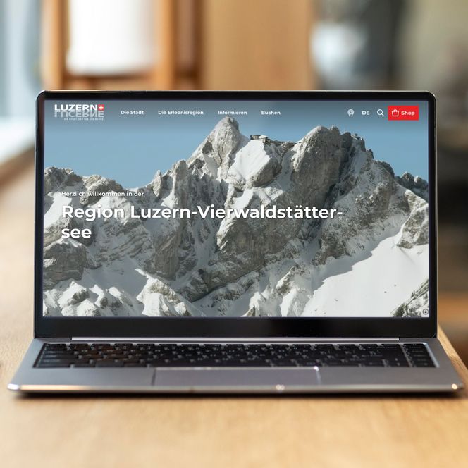Laptop auf einer hölzernen Tischplatte am Fenster zeigt die Website von Luzern